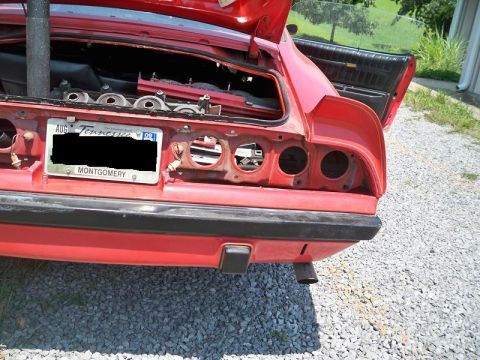 1974 Pontiac Firebird - The rear of a red 1974 Pontiac Firebird is shown with the trunk open and taillights missing, revealing its internal structure.