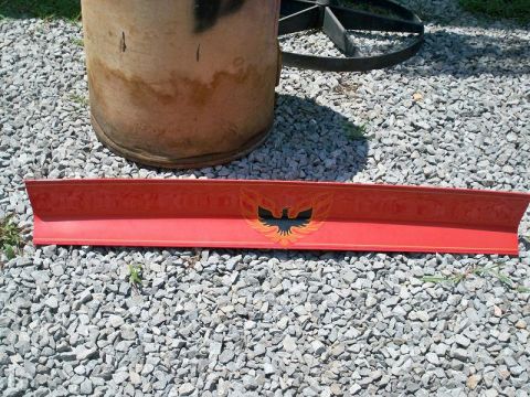 1974 Pontiac Firebird - A red rear spoiler with a phoenix emblem is displayed on a gravel surface.