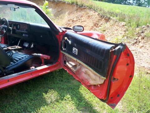 1974 Pontiac Firebird - Interior view of a 1974 Pontiac Firebird with the driver's door open, revealing the dashboard and seats.