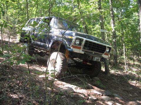 1978 Ford Bronco - A 1978 Ford Bronco navigates a challenging off-road course through a dense forest.