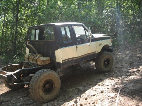 1978 Ford Bronco - This modified pickup truck chassis, equipped with auxiliary fuel tanks, navigates a rocky, wooded trail.