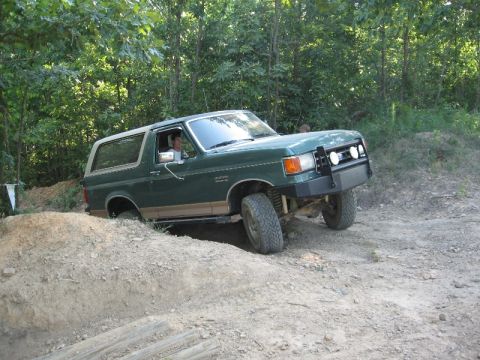 1978 Ford Bronco - This green Ford Bronco is navigating an obstacle on a dirt trail, its off-road capabilities.