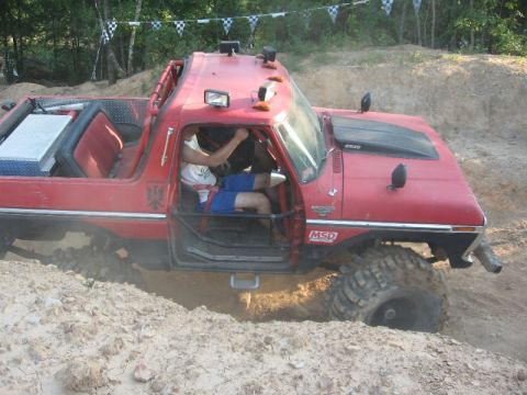 1978 Ford Bronco - This red 1978 Ford Bronco is navigating a challenging off-road course, a roll cage and oversized tires.