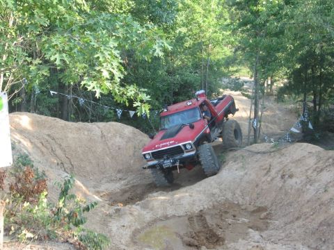 1978 Ford Bronco - This modified truck navigates a challenging off-road course with steep inclines and muddy patches.