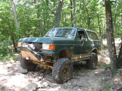 1978 Ford Bronco - Green SUV with off-road modifications navigating a rocky trail.
