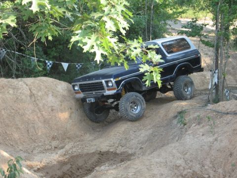 1978 Ford Bronco - A black Ford Bronco navigates a dirt track with checkered flags in the background.