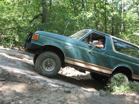 1978 Ford Bronco - Ford Bronco navigates a challenging rocky trail in a wooded area.