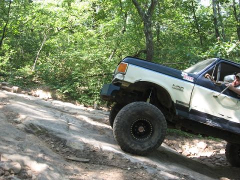1978 Ford Bronco - This modified Ford F-150 navigates a challenging off-road trail with steep inclines and rocky terrain.