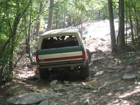 1978 Ford Bronco - Ford Bronco navigates a challenging off-road path through a forest.