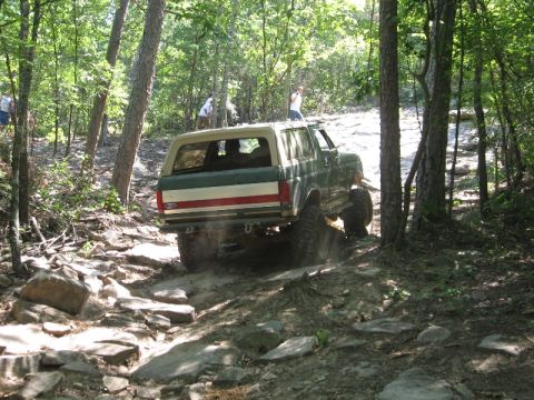 1978 Ford Bronco - This Ford Bronco is navigating a challenging, rocky off-road path through a wooded area.
