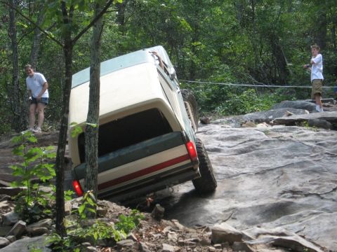 1978 Ford Bronco - A 1978 Ford Bronco maneuvers over a challenging rocky obstacle course with spectators watching.