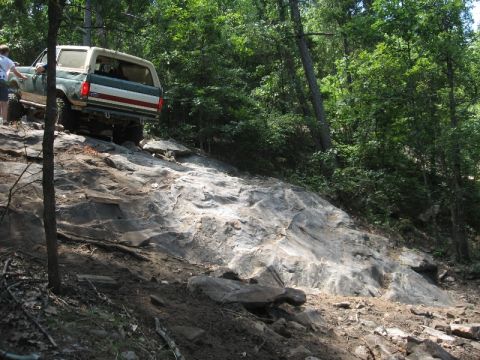 1978 Ford Bronco - A Ford Bronco navigates a challenging off-road trail with steep inclines and large rocks.