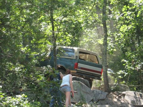 1978 Ford Bronco - Ford Bronco attempting to climb over large rocks in a wooded area.