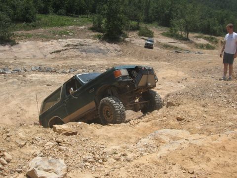 1978 Ford Bronco - Off-road SUV attempts to climb a challenging rocky terrain, with another vehicle in the distance.
