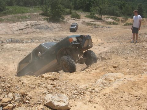 1978 Ford Bronco - An off-road SUV navigates a challenging dirt terrain, with another vehicle visible in the background.