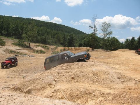 1978 Ford Bronco - Off-road vehicles navigate a dirt course on a sunny day.