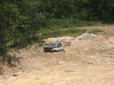 1978 Ford Bronco - A two-tone Ford Bronco drives through a rocky, off-road terrain.