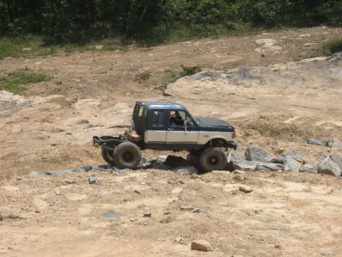 1978 Ford Bronco - Modified truck navigates a rocky terrain with a clear blue sky overhead.