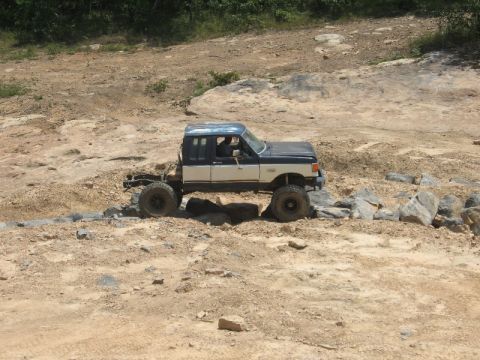 1978 Ford Bronco - This heavily modified pickup truck is shown off-roading on a rocky trail, demonstrating its lifted suspension and large tires.