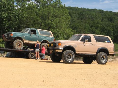 1978 Ford Bronco - Two modified Ford Broncos are present, with one being worked on while loaded onto a trailer.