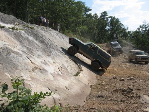 1978 Ford Bronco - Multiple off-road vehicles navigate a challenging rocky incline on a sunny day.