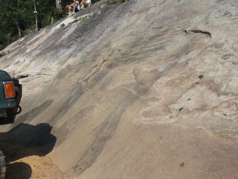1978 Ford Bronco - An off-road vehicle navigates a challenging rocky terrain while spectators observe from the top of the incline.