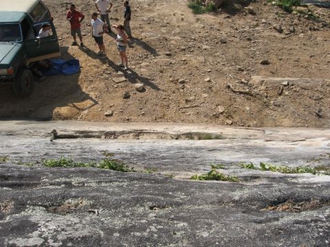 1978 Ford Bronco - A group of people stand around a green SUV parked on a steep, rocky slope.