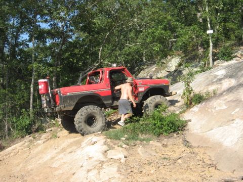 1978 Ford Bronco - This modified 1978 Ford Bronco navigates a challenging off-road course, with its driver stepping out to assess the path ahead.
