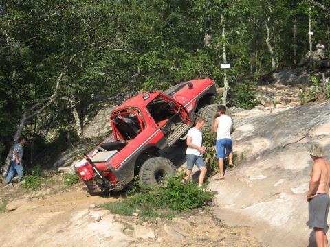 1978 Ford Bronco - This modified off-road vehicle is navigating a steep, rocky incline with assistance from onlookers.