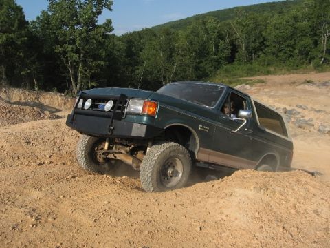 1978 Ford Bronco - This green SUV navigates a dirt hill with its front wheels climbing over an obstacle.