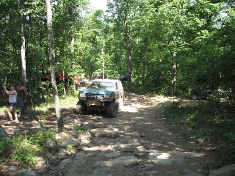 1978 Ford Bronco - Modified 1978 Ford Bronco navigating a rough, wooded trail with other vehicles visible.