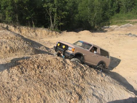 1978 Ford Bronco - This Ford Bronco is navigating a steep, sandy incline with trees in the background.