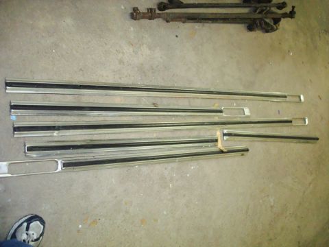 1995 Ford Bronco - Various chrome trim pieces and linkage parts are displayed on a concrete surface.