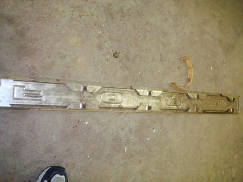 1995 Ford Bronco - A metal trim piece with embossed letters is shown on a concrete surface.