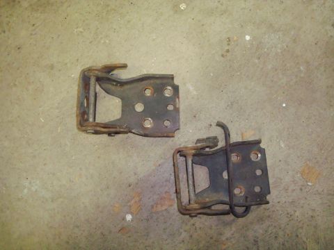 1995 Ford Bronco - These are two old, rusty door hinges lying on a concrete surface. One of the hinges appears to have a bent metal piece.