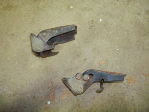 1995 Ford Bronco - Two old, rusty hood latch mechanisms are shown on a concrete surface.