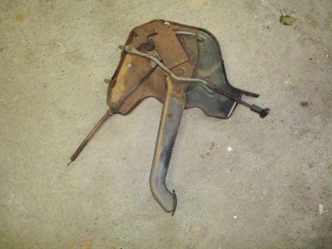 1995 Ford Bronco - Rusty brake pedal assembly with linkage and cable, likely for an older vehicle.