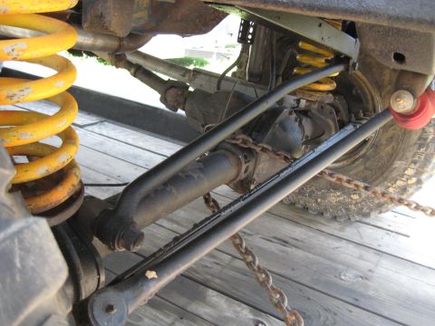 1978 Ford Bronco - The underside of an off-road vehicle shows heavy-duty suspension components and chains securing the axle.