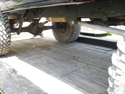 1978 Ford Bronco - Close-up view of the undercarriage and large tires of a vehicle on a wooden surface.