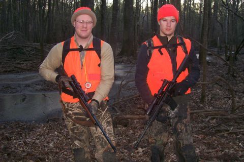 1982 Ford E350 - Two hunters are pictured in a forest, dressed in camouflage and orange safety vests.