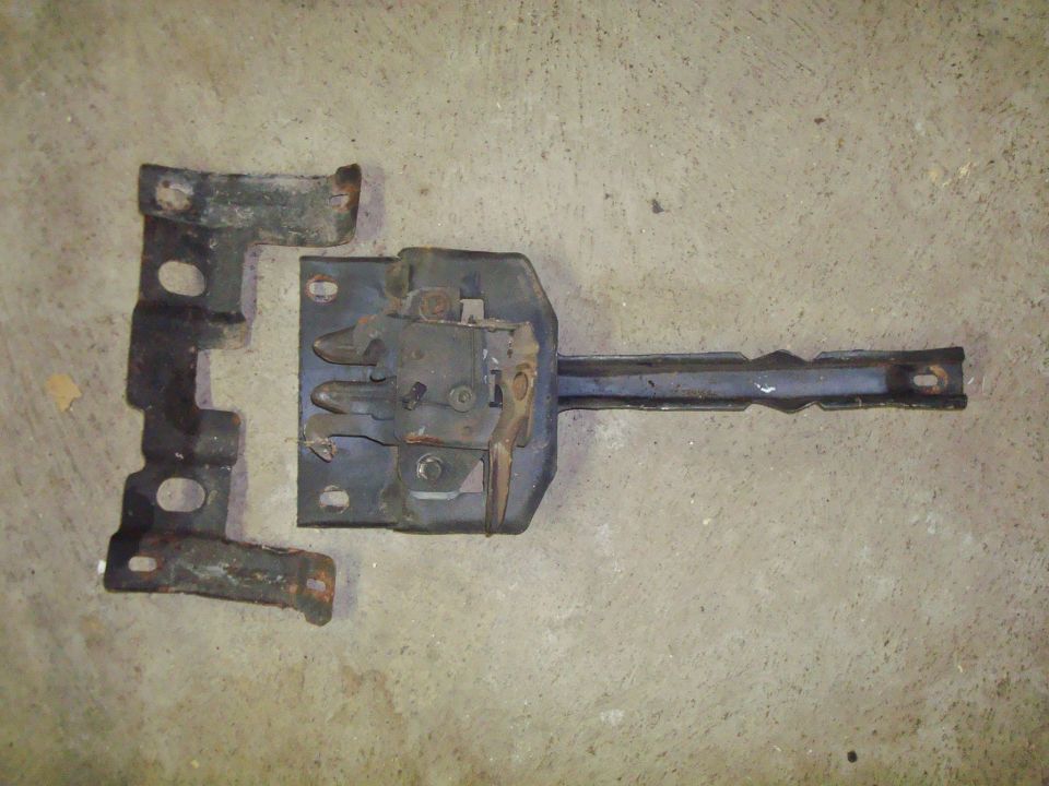 Hood latch assembly and striker plate removed from a vehicle