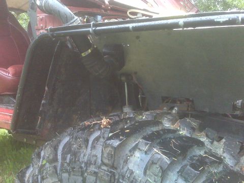 1987 Suzuki Samurai - Close-up view of the interior and suspension of a red off-road vehicle with large tires.