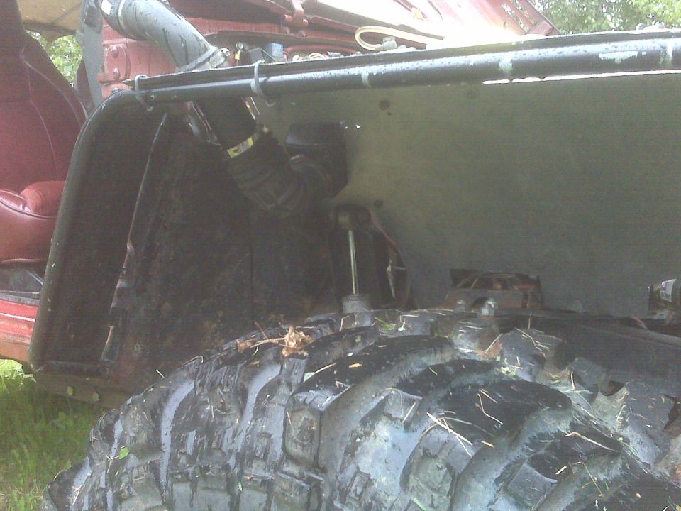 Red off-road vehicle interior and large tire, showing suspension components