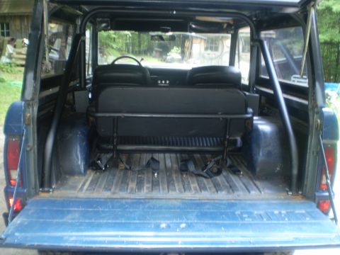 1979 Ford Bronco - The interior of a blue Ford Bronco, viewed from the rear, reveals its cargo space and seating arrangement.