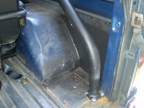 1979 Ford Bronco - Interior view of the rear wheel well and roll bar in a blue vehicle.