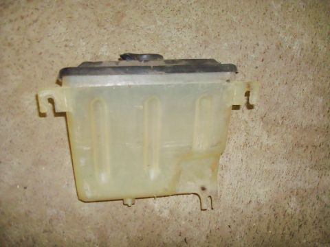 1995 Ford Bronco - Plastic coolant reservoir with black cap, photographed against a concrete wall.