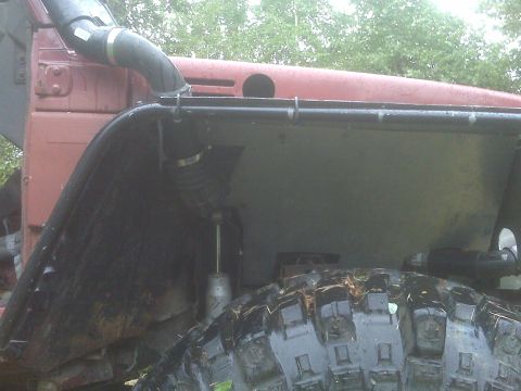 1987 Suzuki Samurai - Close-up view of a red off-road vehicle's fender, snorkel, and aggressive tire tread.