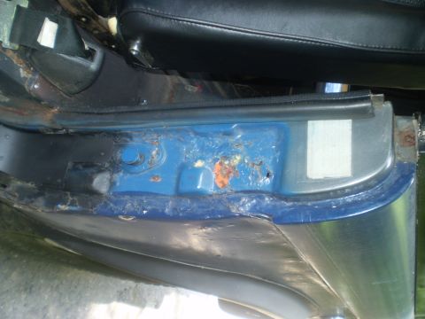 1979 Ford Bronco - Door sill area shows significant rust and damage. Part of the interior seat is visible.