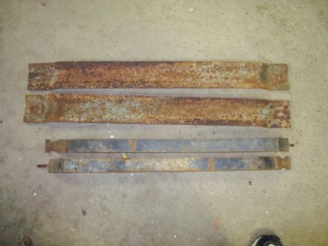 1995 Ford Bronco - Four heavily rusted metal components are displayed on a concrete surface, likely for sale or identification.