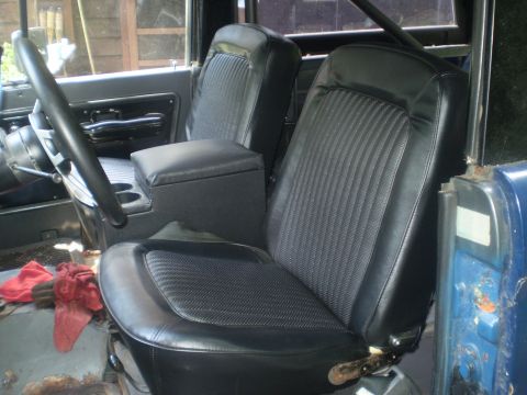 1979 Ford Bronco - The interior features black bucket seats with a ribbed pattern and a central console with cup holders.
